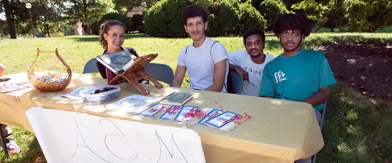 students sitting behind a club table at an event